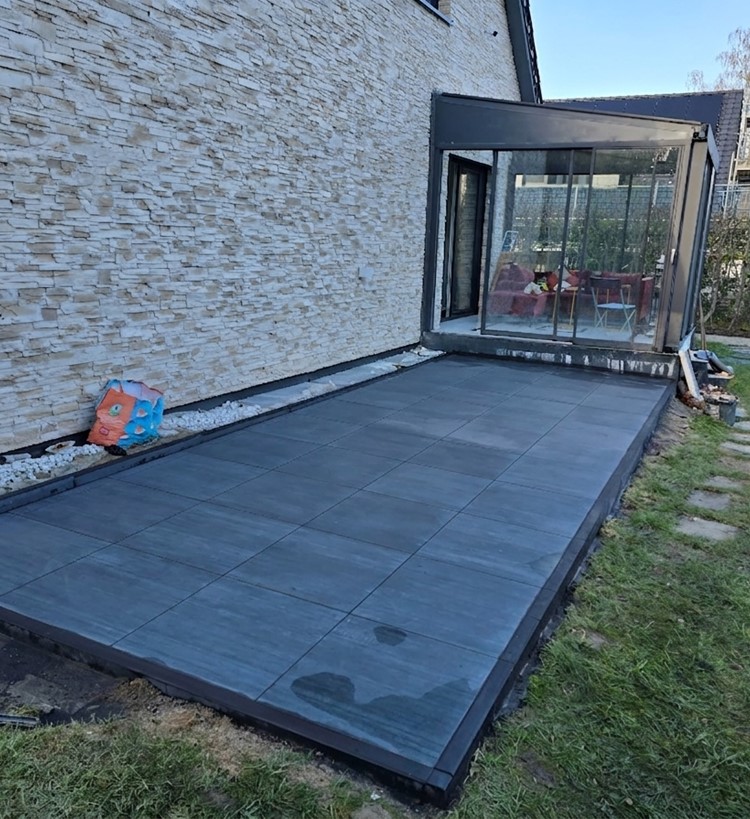 Terrasse mit anthrazitfarbenen Großformatplatten vor Glasanbau – DreieckBau Peine