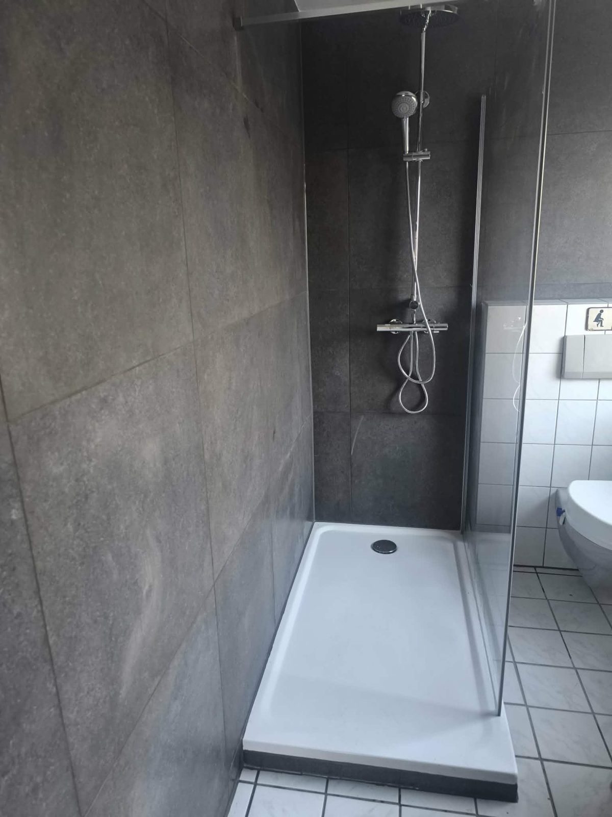 Badsanierung Peine – Dusche mit anthrazitfarbenen Großformatfliesen und flacher Duschwanne